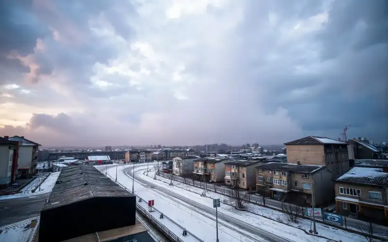 Zaśnieżone ulice polskiego miasta spowite mgłą pod dramatycznym niebem burzowym zimą