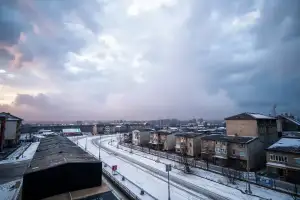 Zaśnieżone ulice polskiego miasta spowite mgłą pod dramatycznym niebem burzowym zimą